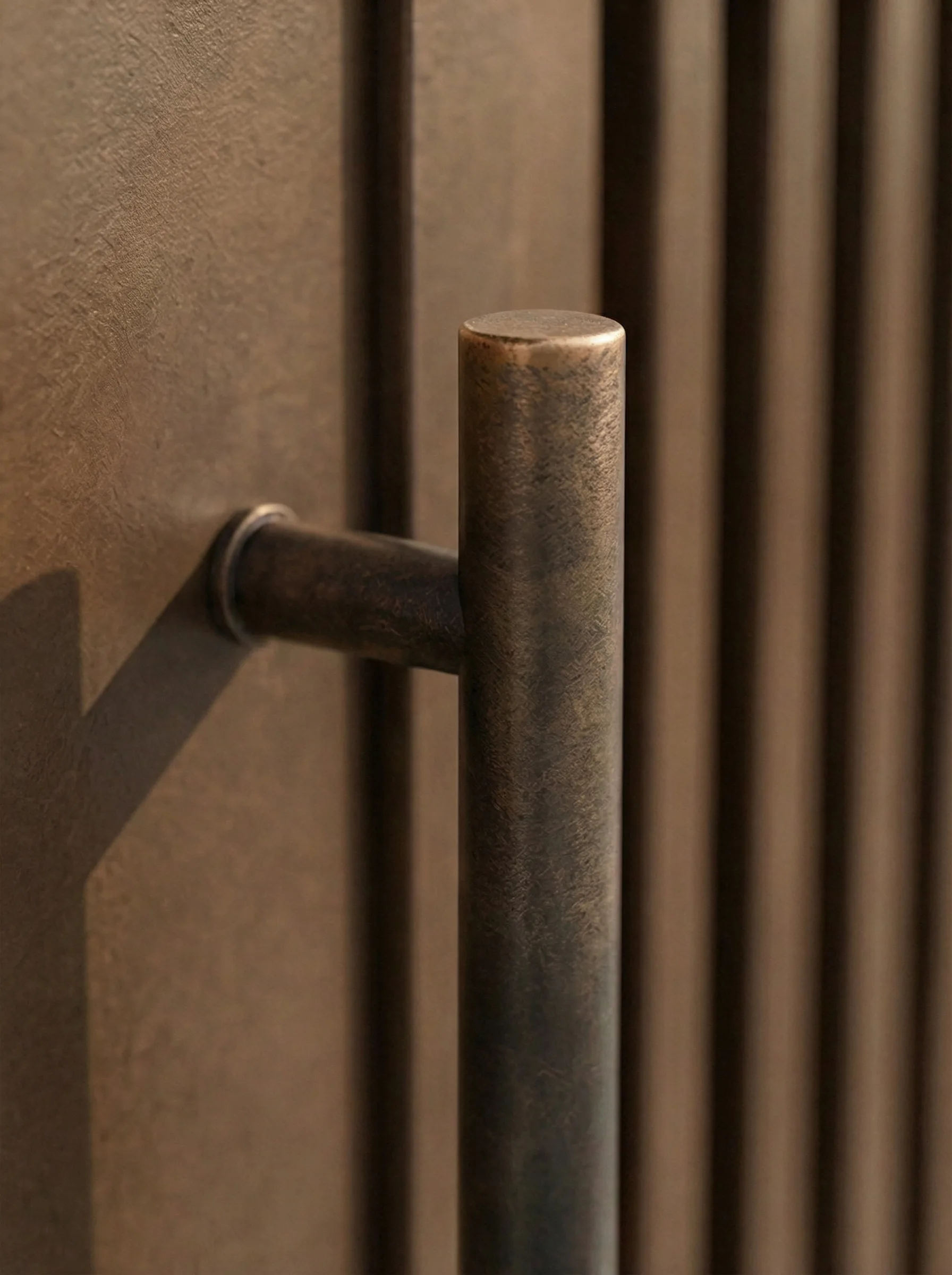 A close-up of a cylindrical bronze handle on a vertical-slat door