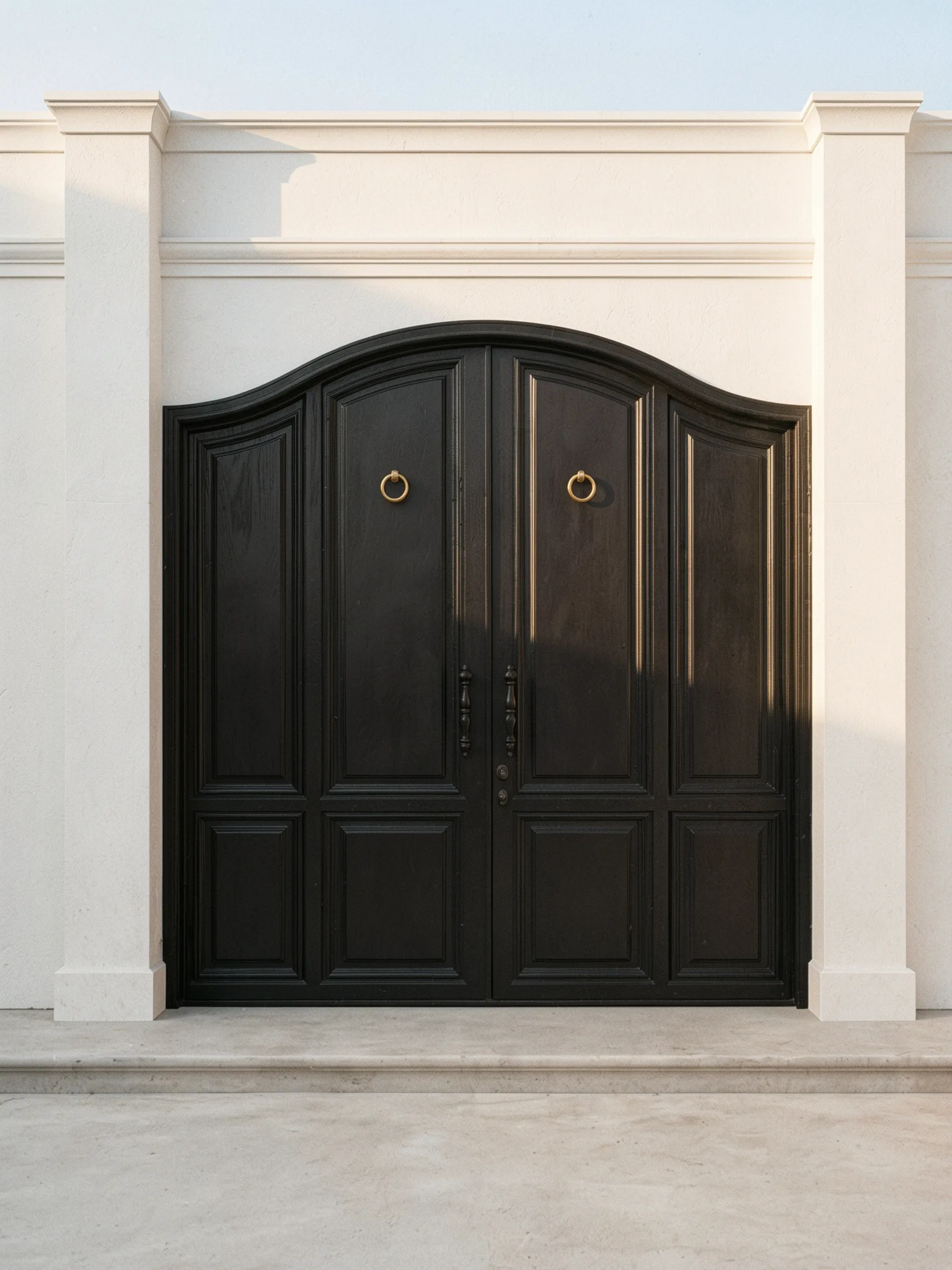 A black double steel door with an arched crown and classical detailing — Side angle
